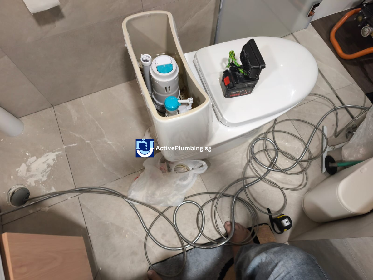 Plumber clearing a clogged toilet bowl drainage pipe in a Singapore bathroom.