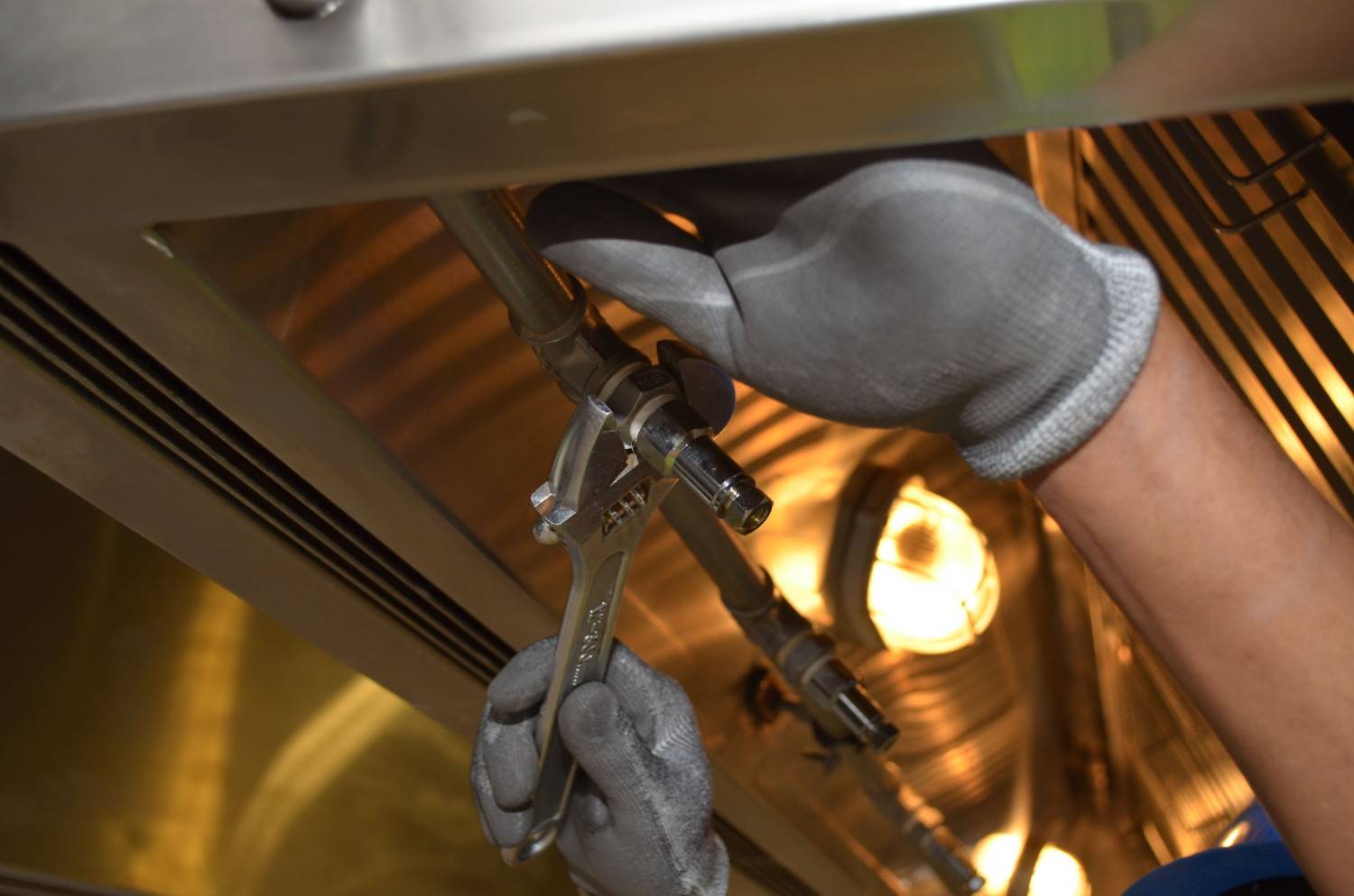 A worker fixing pipes with tools in an industrial indoor environment